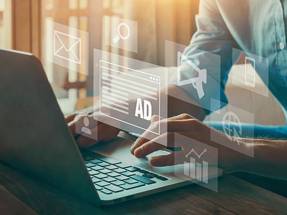 person using a laptop with graphics and the word 'ad' floating above the keyboard